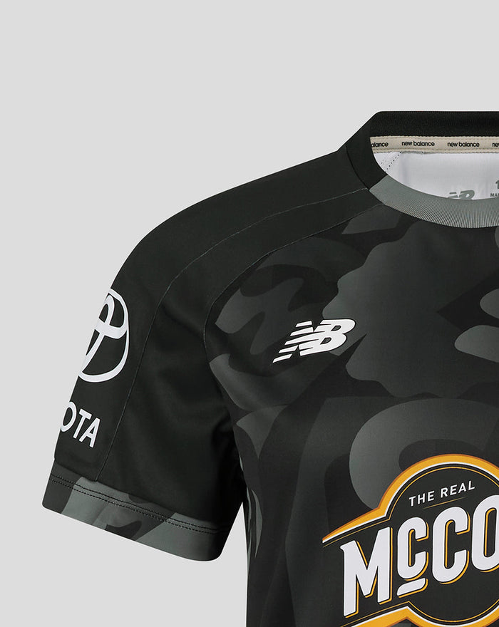 Close up of a black camouflage Manchester Originals replica shirt with the NB logo and sponsor emblem.