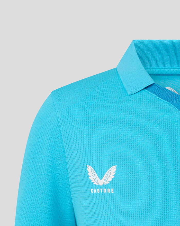 Shoulder close up of a bright blue cricket shirt with white Castore wing logo.