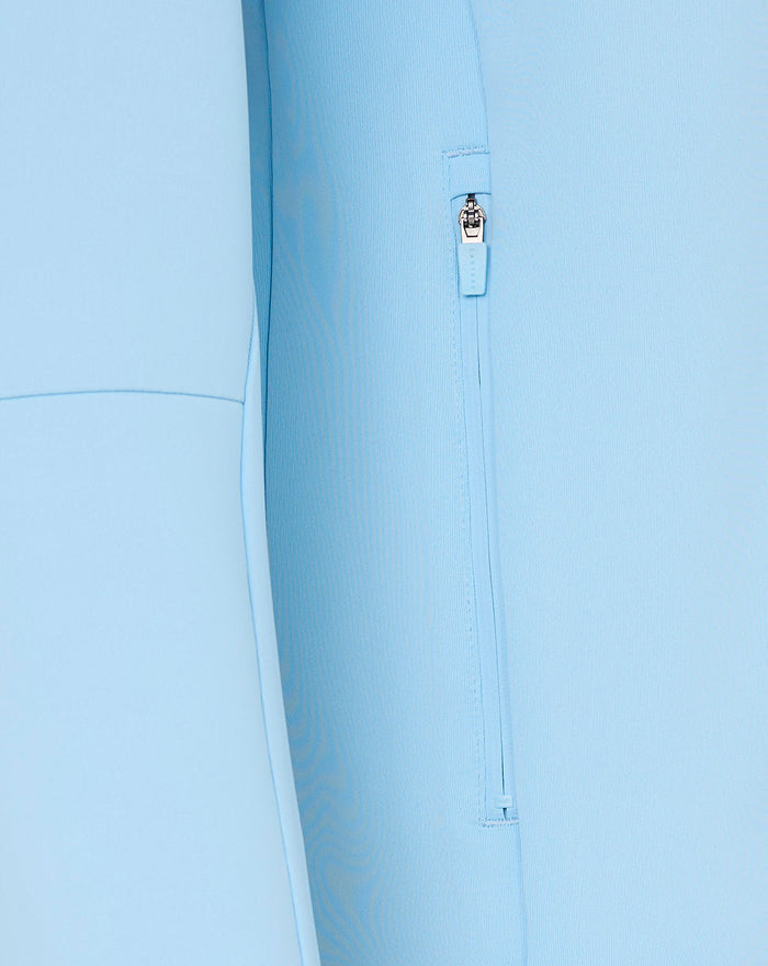 Close-up of light blue hoodie side zipper pocket with pull tag.