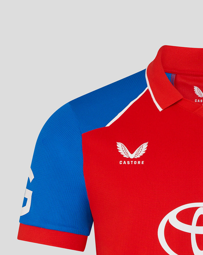 Close-up of red jersey chest with England crest and Castore branding against a blue sleeve