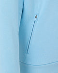 Close up of a light blue hoodie showing a vertical zip pocket detail