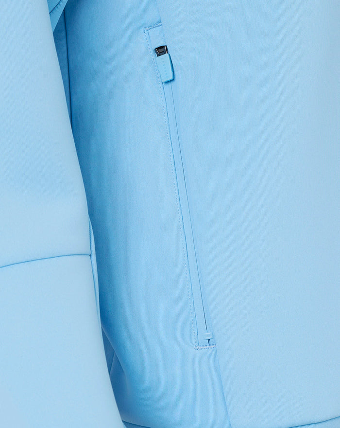 Close-up of light blue Travel Flex Full Zip Hoodie fabric showing a zippered side pocket.