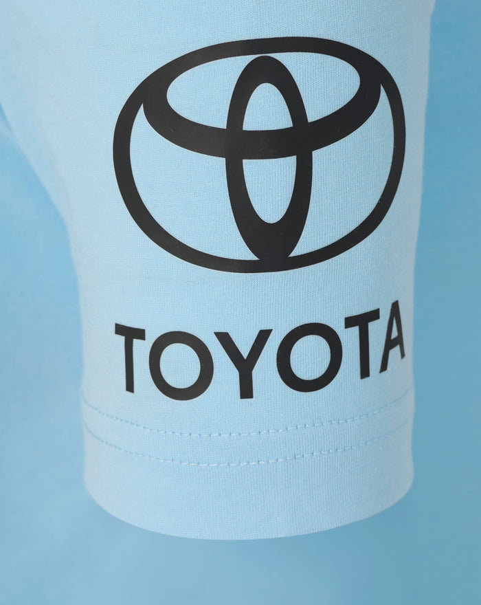 Close up of light blue polo fabric with large black Toyota logo across chest