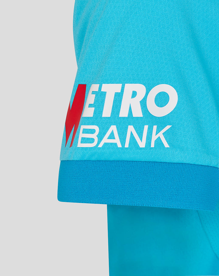 Womens ODI Pro short sleeve blue shirt close-up showing Metro Bank logo on the front hem.