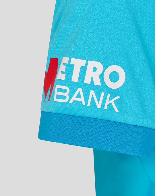 Sleeve close up showing Metro Bank logo patch on bright blue cricket shirt
