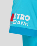 Sleeve close up showing Metro Bank logo patch on bright blue cricket shirt