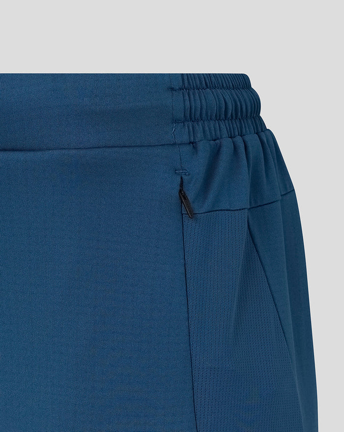 Close-up of the blue training pants waistband with elastic band and zip pocket detail.