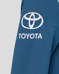Close up of blue athletic fabric with a white Toyota logo on the sleeve