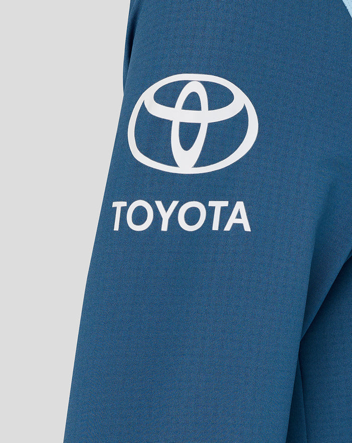 Close up of blue athletic fabric with a white Toyota logo on the sleeve