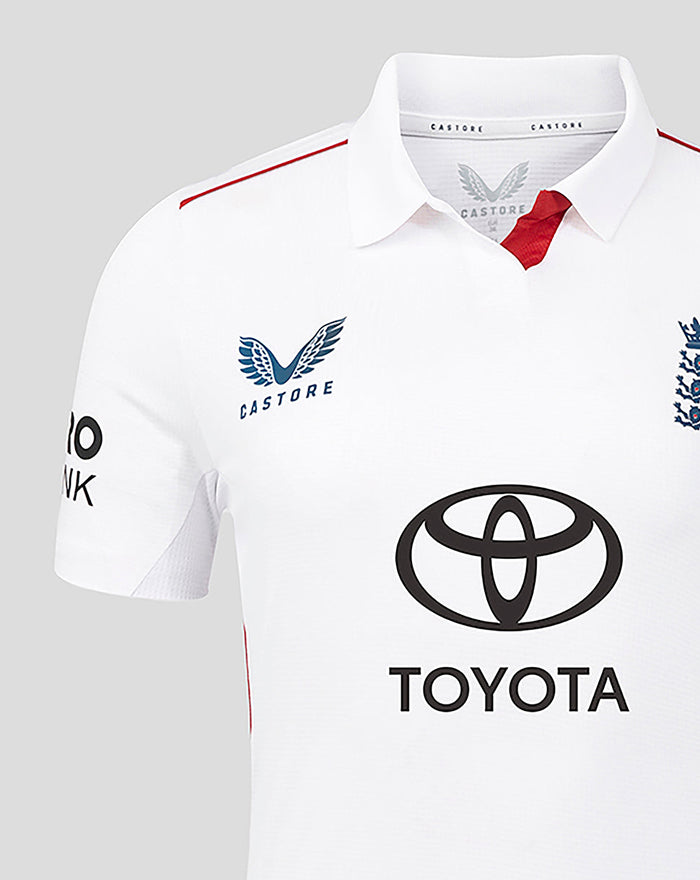 White England women's Test cricket shirt with navy Castore crest on the left, England three lions badge on the right, Toyota sponsor, and red shoulder trim.