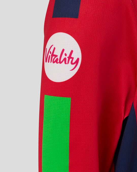 Red junior T20 jersey sleeve close up with a white Vitality circular logo and a bright green panel