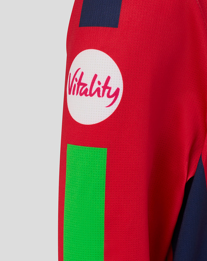Red junior T20 jersey sleeve close up with a white Vitality circular logo and a bright green panel