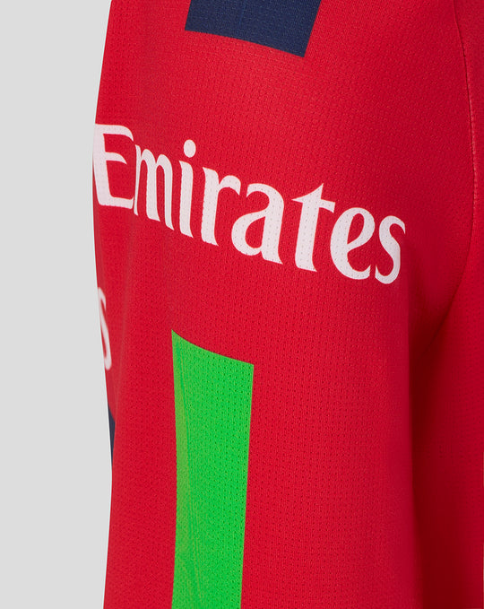 Red junior T20 jersey side view showing Emirates sponsor and Castore wing logo with a navy shoulder patch