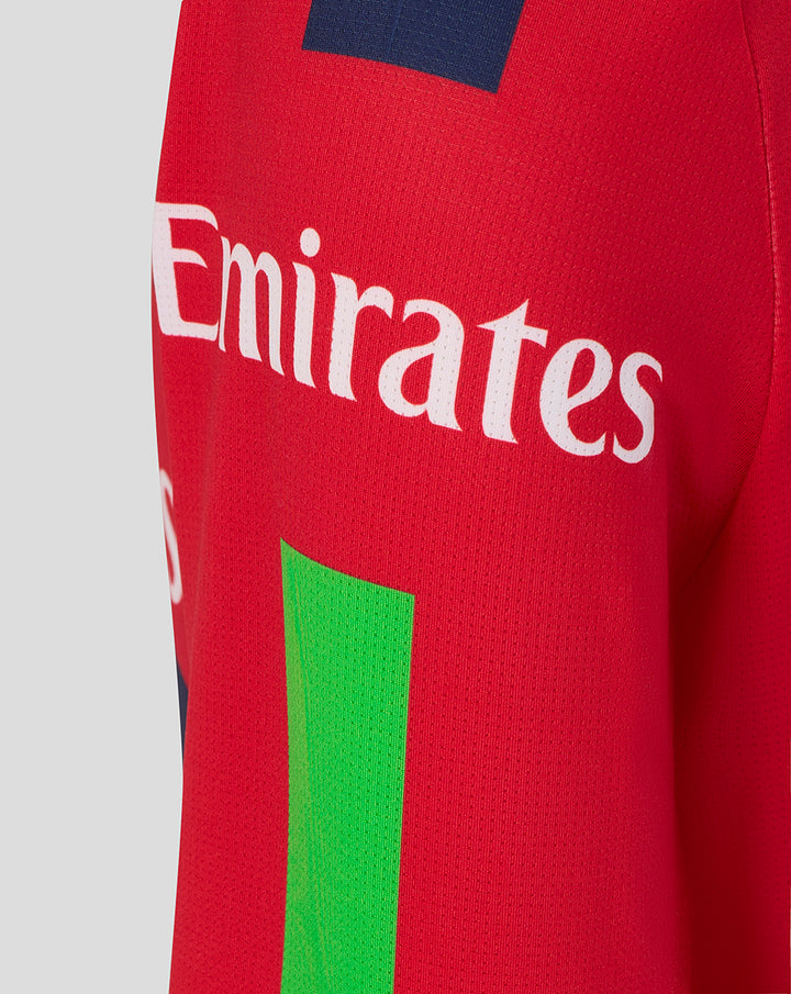 Red junior T20 jersey side view showing Emirates sponsor and Castore wing logo with a navy shoulder patch