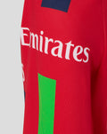 Red junior T20 jersey side view showing Emirates sponsor and Castore wing logo with a navy shoulder patch