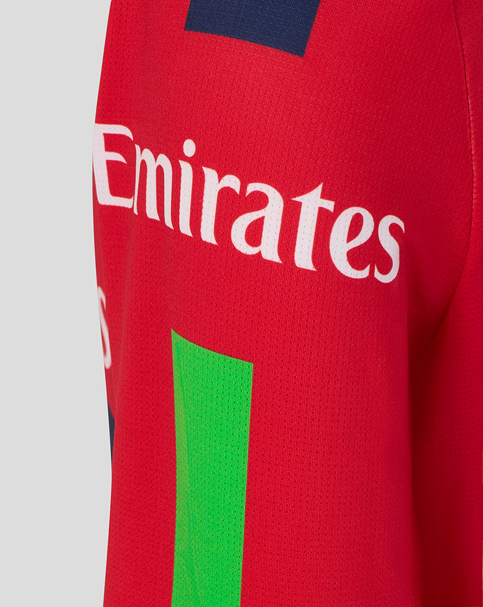Red junior T20 jersey side view showing Emirates sponsor and Castore wing logo with a navy shoulder patch