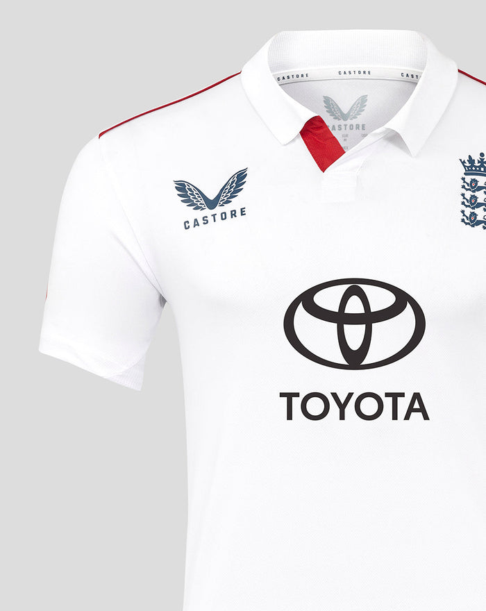 Close up of a white polo cricket shirt showing Castore branding on the left chest and a red sleeve stripe.