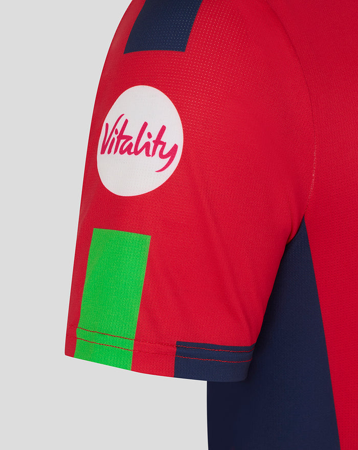 Close-up of the red sleeve showing Vitality logo and bright green panel with navy trim.