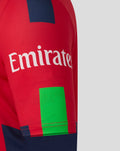 Close-up of a red T20 cricket jersey with Emirates sponsor across the chest and bold blue and lime graphic blocks on the sleeve.
