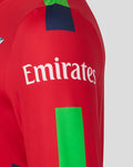 Red sweatshirt sleeve with Emirates sponsor logo and a vivid green rectangular accent.