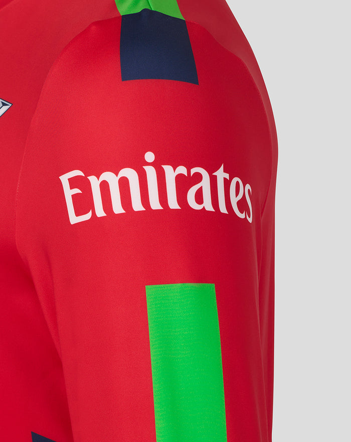Red sweatshirt sleeve with Emirates sponsor logo and a vivid green rectangular accent.