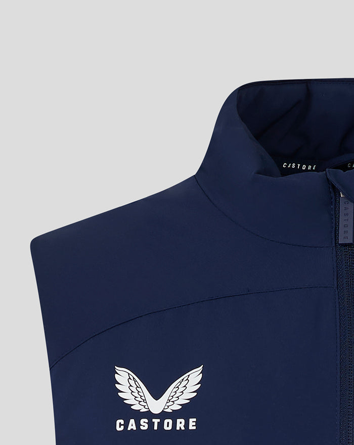 Close-up of navy padded gilet chest showing white Castore logo and zipper pull at the collar.